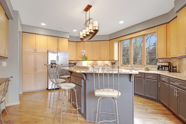 780 Virginia Shores Cir, Excelsior, MN 55331 - kitchen with stainless steel refrigerator with ice dispenser, light stone countertops, a breakfast bar area, tasteful backsplash, and light wood-style flooring
