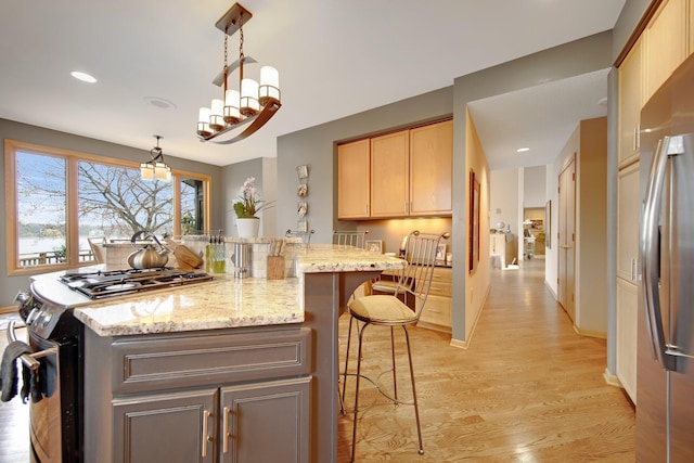 780 Virginia Shores Cir, Excelsior, MN 55331 - kitchen with appliances with stainless steel finishes, a breakfast bar area, light wood-style floors, light stone counters, and decorative light fixtures