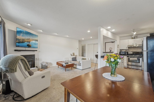 living area featuring light carpet, a fireplace, and recessed lighting