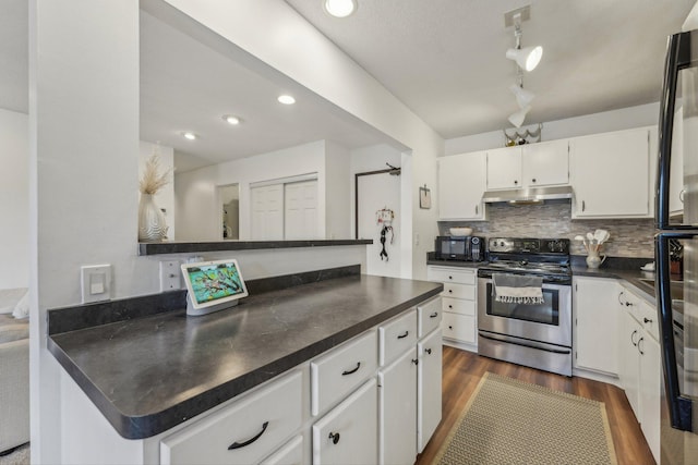 kitchen with dark countertops, stainless steel electric range, white cabinets, under cabinet range hood, and dark wood-style floors