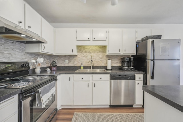 kitchen featuring dark countertops, a sink, appliances with stainless steel finishes, white cabinetry, and under cabinet range hood