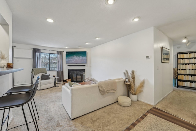 living area with baseboards, a glass covered fireplace, wood finished floors, and recessed lighting
