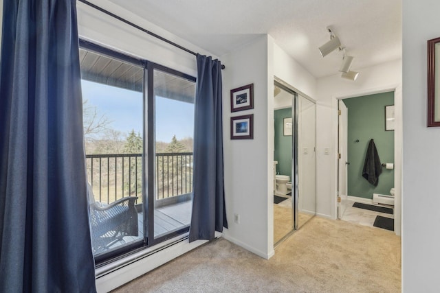 interior space featuring baseboard heating, carpet flooring, and a healthy amount of sunlight
