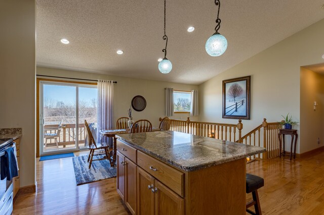 26141 Jonquil Ave, New Market Twp, MN 55020 - kitchen with a textured ceiling, a breakfast bar, light wood-style floors, plenty of natural light, and brown cabinets