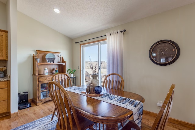 26141 Jonquil Ave, New Market Twp, MN 55020 - dining space featuring a wood stove, light wood-type flooring, a textured ceiling, vaulted ceiling, and baseboards