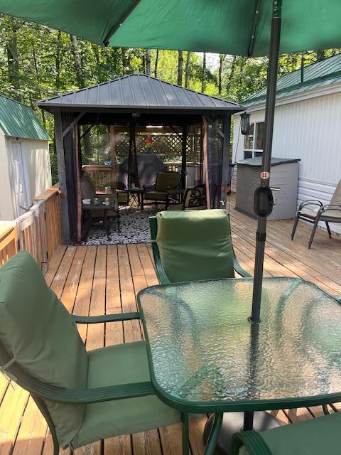 wooden terrace featuring a gazebo and outdoor dining area
