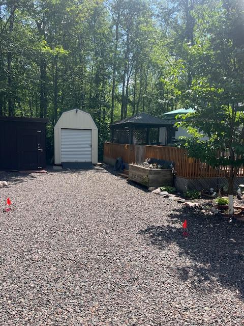view of yard with gravel driveway, a garage, an outbuilding, and a shed