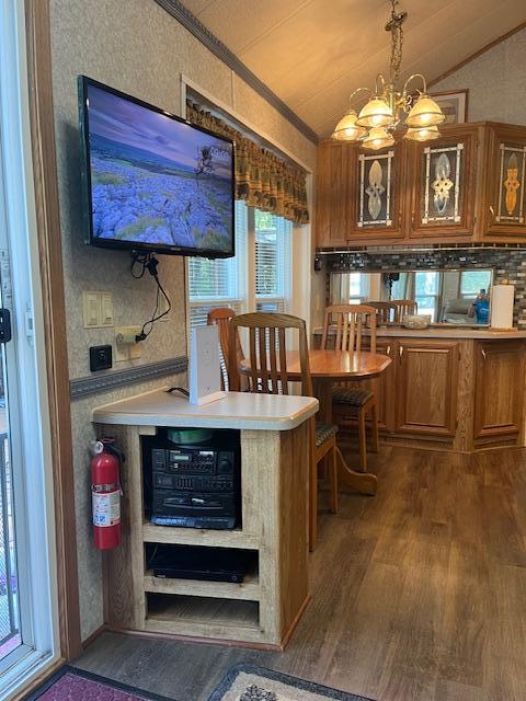 kitchen featuring crown molding, vaulted ceiling, an inviting chandelier, dark wood finished floors, and brown cabinets