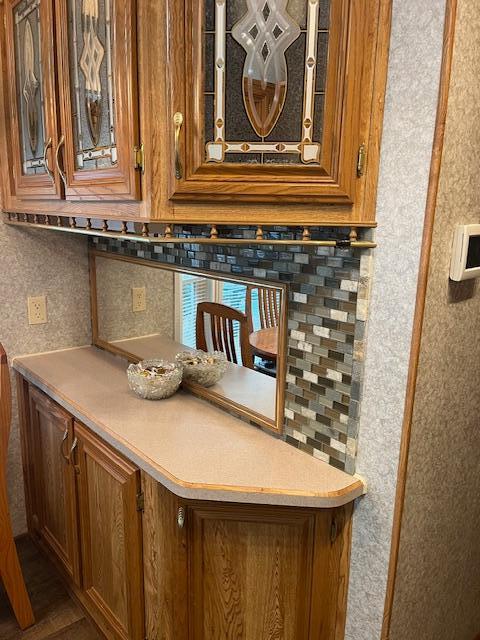 interior space with light countertops, wood finished floors, glass insert cabinets, and brown cabinets