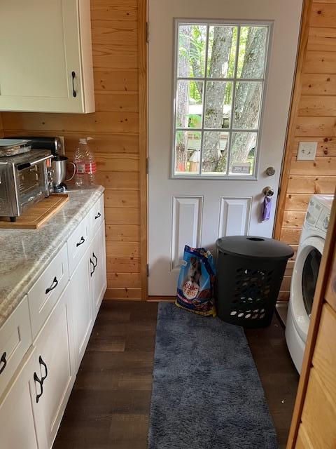 washroom featuring dark wood-type flooring, a toaster, washer / clothes dryer, wooden walls, and laundry area