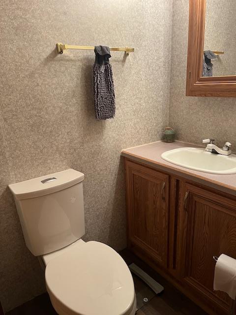 bathroom with wallpapered walls, toilet, and vanity