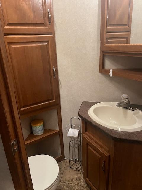 bathroom featuring tile patterned floors, a textured wall, toilet, and vanity
