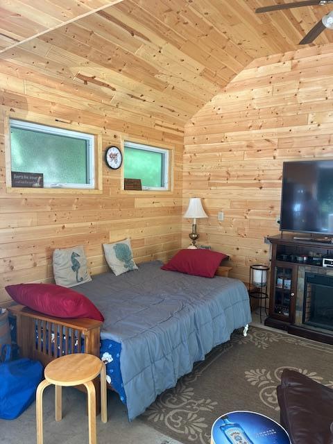 bedroom with lofted ceiling, wooden walls, and wood ceiling