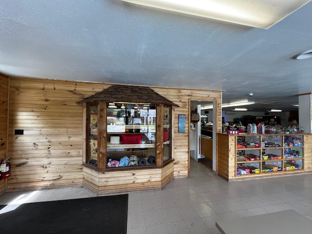interior space featuring tile patterned floors, wooden walls, and a textured ceiling