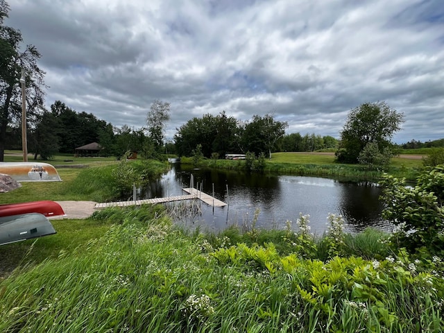view of property's community featuring a yard, a water view, and a boat dock