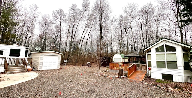 view of yard with a detached garage, an outdoor structure, and a deck