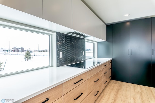 8030 59th St S, Horace, ND 58047 - kitchen featuring black electric stovetop, range hood, light countertops, light wood-style flooring, and modern cabinets