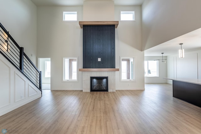 8030 59th St S, Horace, ND 58047 - unfurnished living room with a towering ceiling, stairway, light wood-style floors, a fireplace, and plenty of natural light