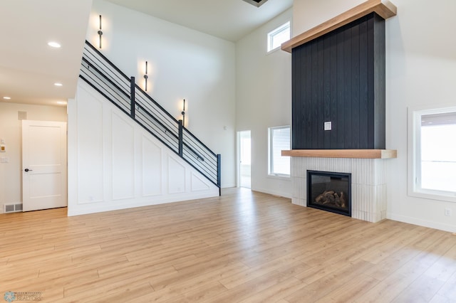 8030 59th St S, Horace, ND 58047 - unfurnished living room with a fireplace, light wood-style floors, a high ceiling, stairs, and recessed lighting