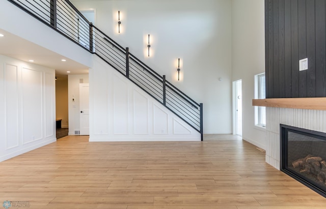 8030 59th St S, Horace, ND 58047 - unfurnished living room with a towering ceiling, light wood finished floors, a fireplace, baseboards, and recessed lighting