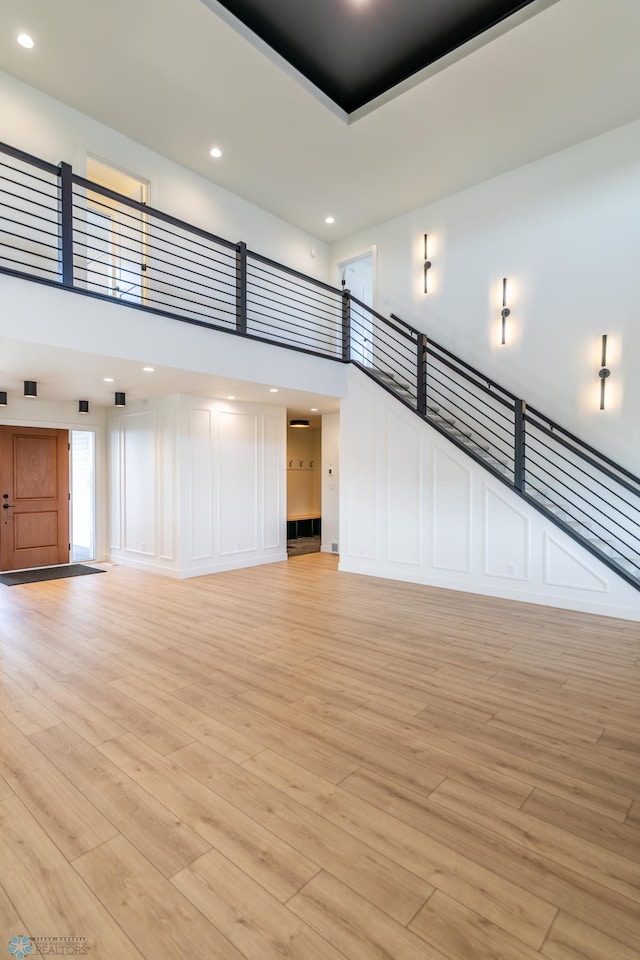 8030 59th St S, Horace, ND 58047 - unfurnished living room with a decorative wall, a towering ceiling, light wood-style flooring, and recessed lighting