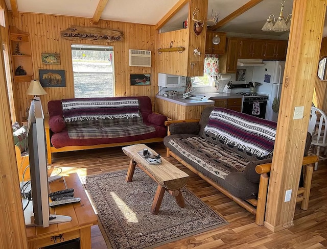 living area featuring a wall unit AC, wooden walls, wood finished floors, and beam ceiling