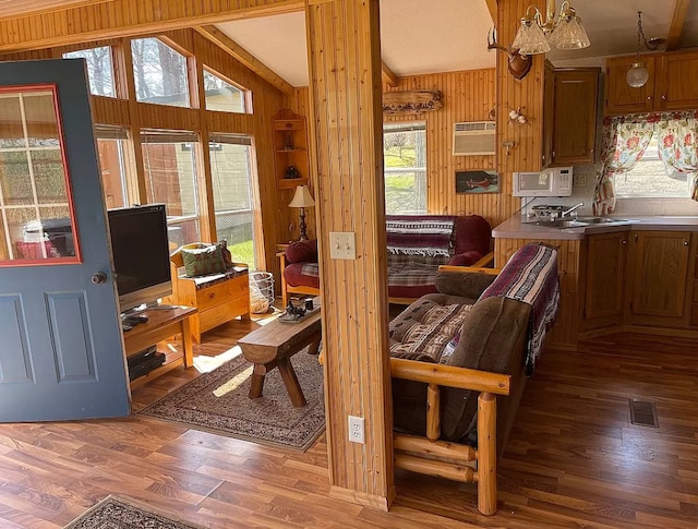 living room featuring visible vents, wood walls, lofted ceiling, and wood finished floors