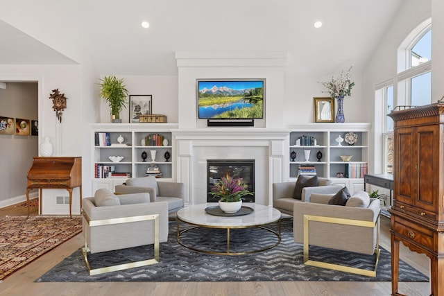 sitting room featuring a glass covered fireplace, recessed lighting, wood finished floors, and lofted ceiling