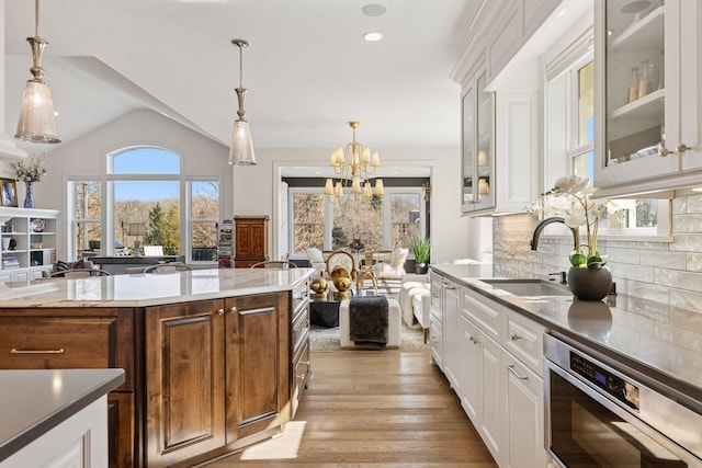 kitchen with white cabinetry, an inviting chandelier, decorative backsplash, and a sink