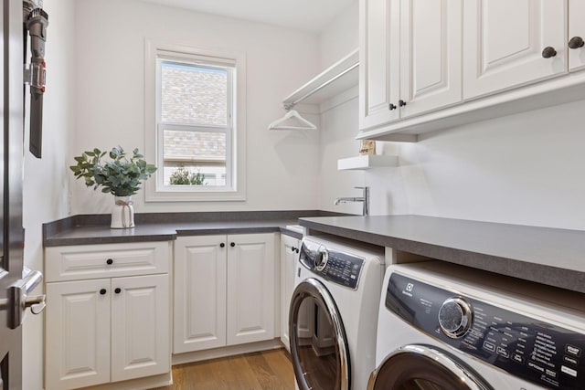 laundry area with light wood-style floors, a sink, cabinet space, and washing machine and dryer