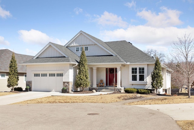 craftsman inspired home featuring board and batten siding, driveway, an attached garage, a shingled roof, and stone siding