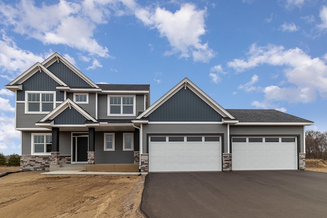 craftsman-style house featuring stone siding, an attached garage, and driveway