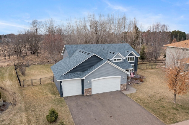 view of front of property featuring a front lawn, fence, roof with shingles, an attached garage, and driveway