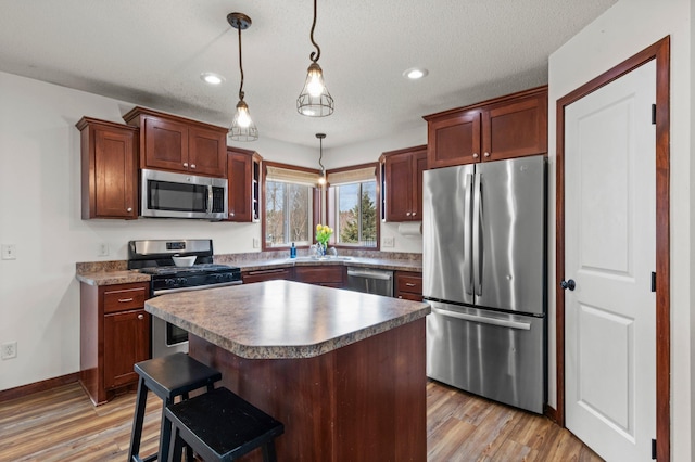 kitchen featuring stainless steel appliances, hanging light fixtures, recessed lighting, and light wood-type flooring