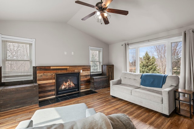 living room featuring a ceiling fan, vaulted ceiling, a fireplace with flush hearth, and wood finished floors