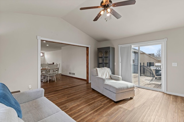 living area with a ceiling fan, visible vents, lofted ceiling, and light wood-type flooring
