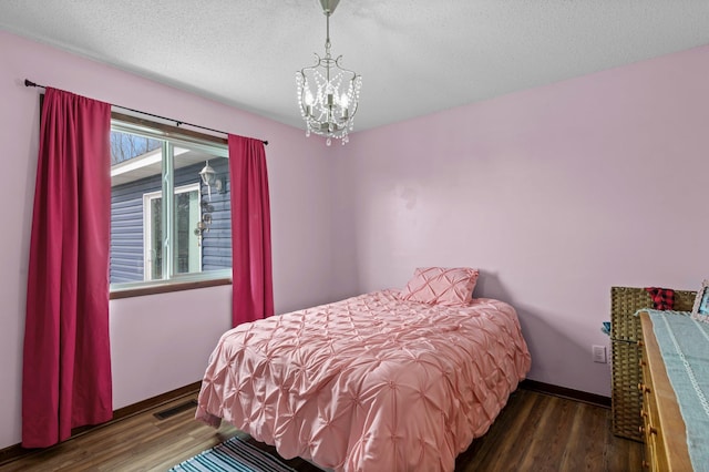 bedroom with an inviting chandelier, baseboards, wood finished floors, and visible vents