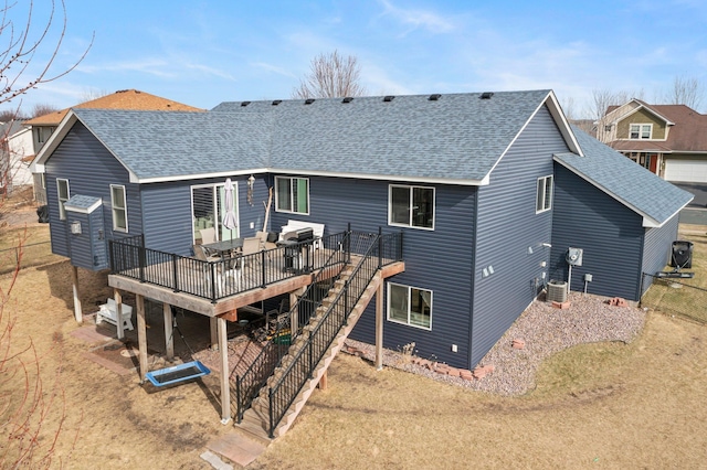 rear view of house featuring central AC, a wooden deck, stairs, and roof with shingles