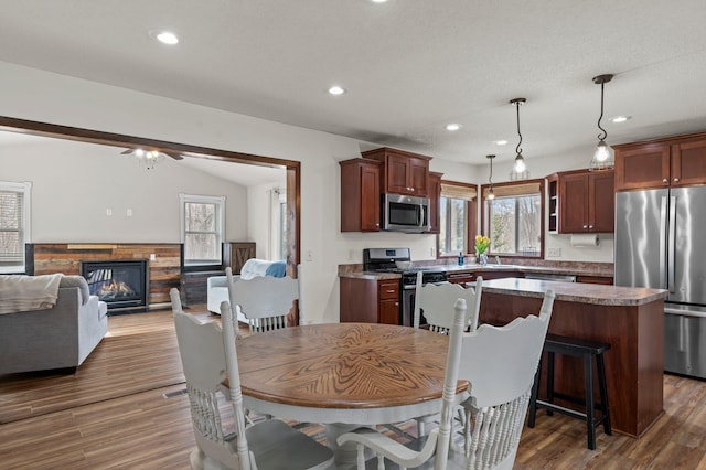 dining space featuring a glass covered fireplace, ceiling fan, recessed lighting, and wood finished floors