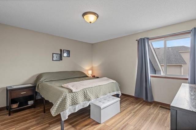 bedroom with light wood-style floors, baseboards, and visible vents