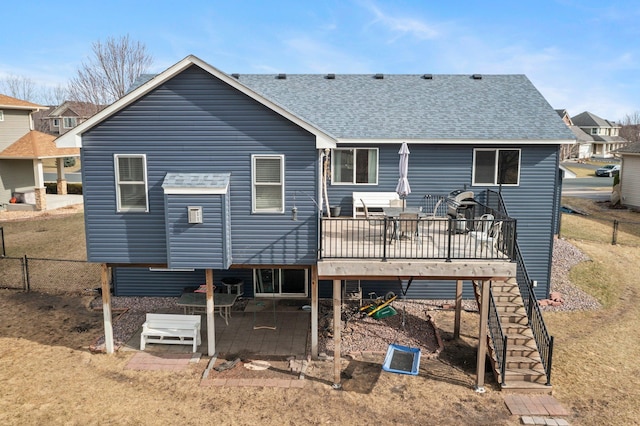 rear view of property with fence, a deck, a patio, a shingled roof, and stairway