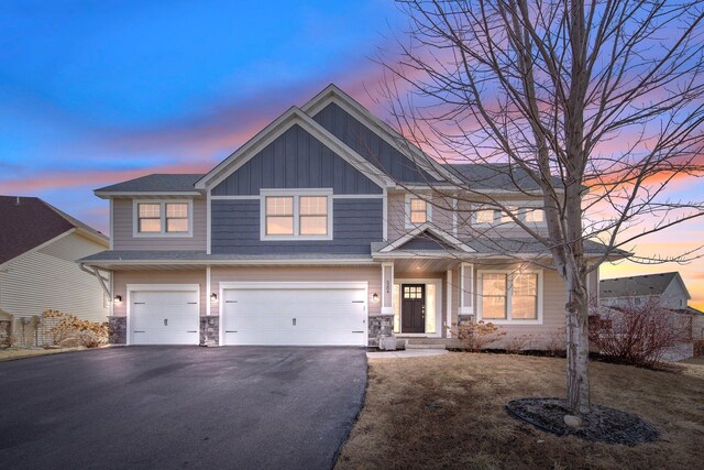 5204 Porchlight, Woodbury, MN 55129 - craftsman house featuring aphalt driveway, stone siding, a garage, and board and batten siding