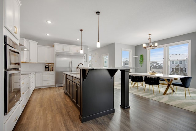 5204 Porchlight, Woodbury, MN 55129 - kitchen with white cabinetry, a notable chandelier, wood finished floors, and appliances with stainless steel finishes
