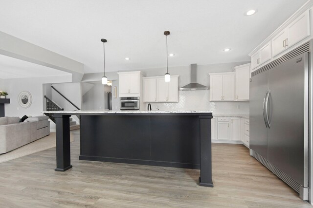 5204 Porchlight, Woodbury, MN 55129 - kitchen featuring light wood-style floors, appliances with stainless steel finishes, wall chimney range hood, open floor plan, and backsplash