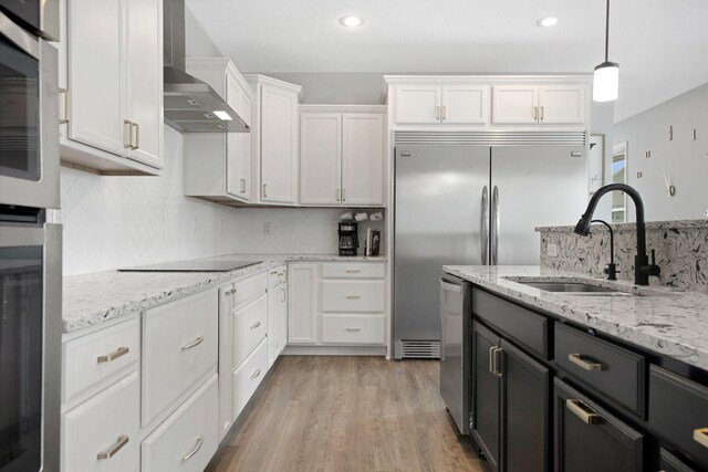 5204 Porchlight, Woodbury, MN 55129 - kitchen featuring a sink, backsplash, white cabinetry, appliances with stainless steel finishes, and wall chimney exhaust hood
