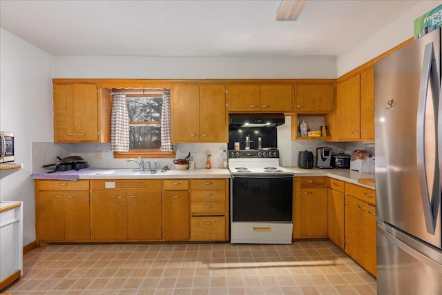 kitchen with light countertops, under cabinet range hood, a sink, and stainless steel appliances