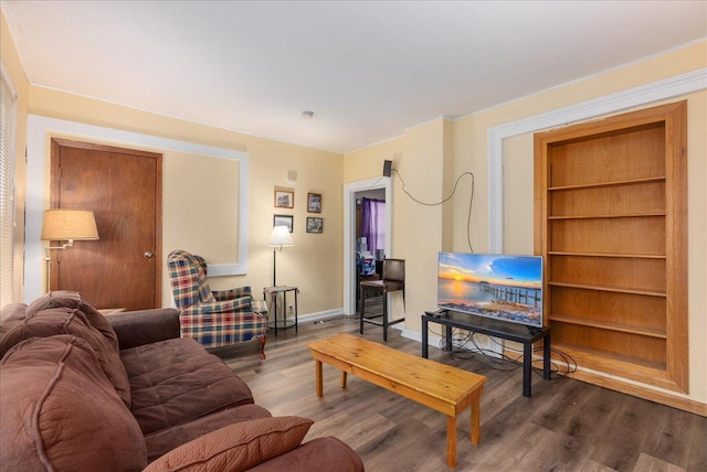 living area featuring baseboards, built in shelves, and wood finished floors