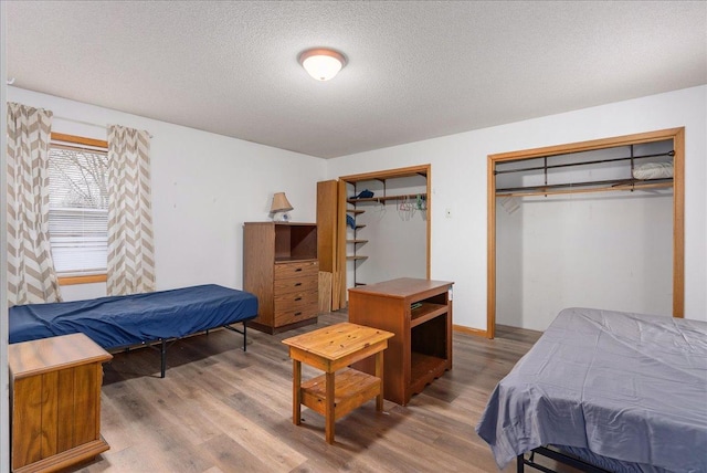 bedroom featuring multiple closets, wood finished floors, and a textured ceiling
