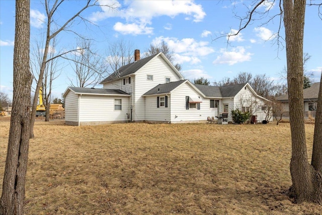 back of house with a chimney and a yard