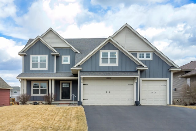 craftsman-style home with an attached garage, roof with shingles, board and batten siding, and driveway